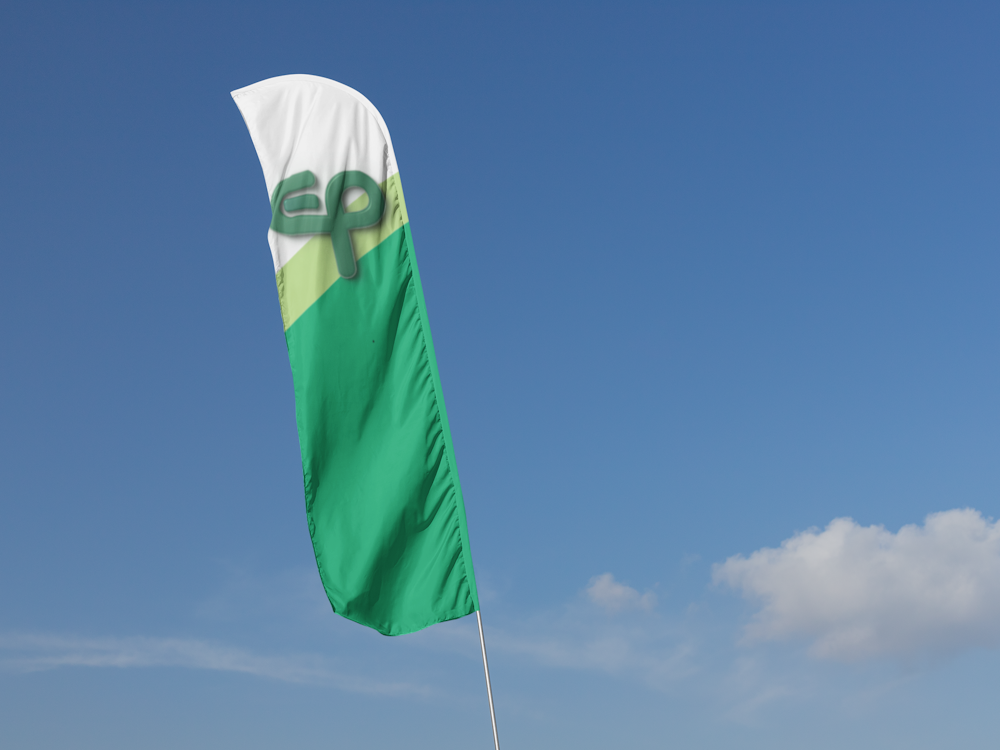 Zastava u zelenim bojama brenda s logom na pozadini plavog neba