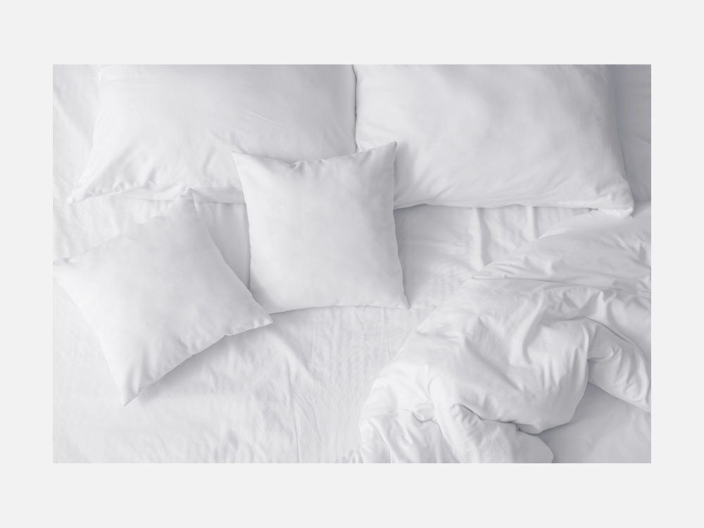 Bijeli komplet posteljine s napunjenim jastucima na krevetu