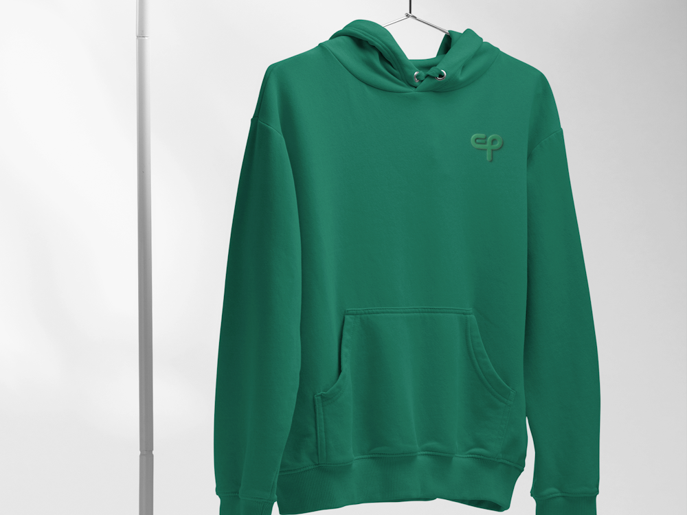 Zelena hoodie majica s kapuljačom i tiskom loga, sportska duksa, visi na bijelom stalku i svijetloj pozadini